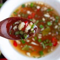 a wooden spoon filled with soup on top of a white plate