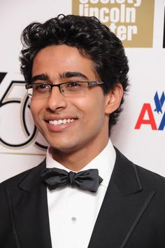 a man in a tuxedo and bow tie smiles for the camera at an awards event