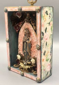 an ornate box with a statue in the center and flowers on it's sides