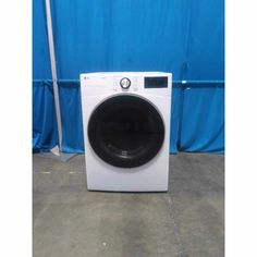 a white washer sitting in front of a blue wall with a black knob on it