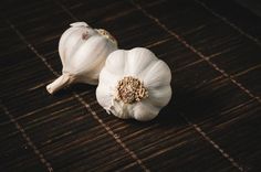 two garlics sitting on top of a wooden table