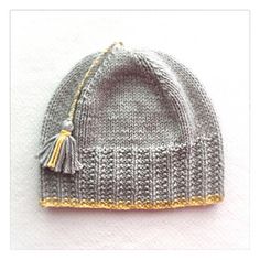 a gray and yellow knitted hat with tassels on the brimmed