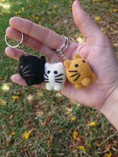 someone is holding two small key chains in their hand, one has a cat and the other has a kitten