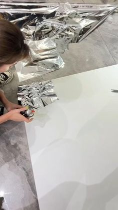 a woman is working on a piece of art that looks like aluminum foil with scissors