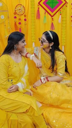 two women dressed in yellow sitting next to each other