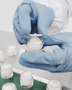 a person in blue gloves is holding a jar with some white stuff on top of it