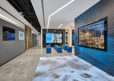 an office lobby with blue chairs and large pictures on the wall