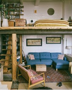 a loft bed with a couch underneath it and bookshelves on the wall above