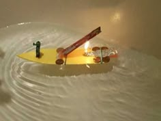 a yellow surfboard floating in the water with candles on it's side and two people standing next to it