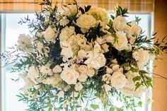 a vase filled with white flowers next to a window