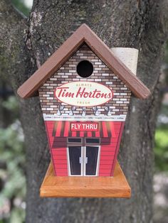 a birdhouse that is hanging from a tree in front of a building with the words tim hortons on it