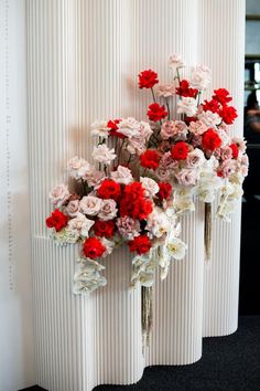 red and white flowers are arranged on the wall