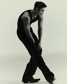 a man in black pants and tank top leaning forward