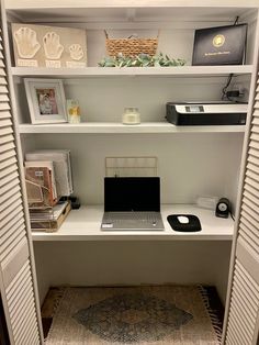 a laptop computer sitting on top of a white desk next to a book shelf filled with books