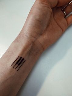 a person's hand with a small tattoo on their left wrist and the other arm