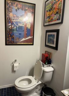 a bathroom with a toilet and pictures on the wall