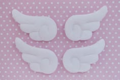 three white angel wings on a pink and white polka dot tablecloth with small dots