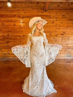 a woman in a white dress and cowboy hat posing for the camera with her hands on her hips