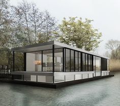 a houseboat floating on top of a lake next to trees and grass in the background