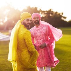 two men dressed in bright yellow and pink are posing for a photo on the grass