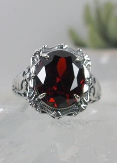 "Red Garnet Ring (Choose Garnet CZ or a Natural Red Garnet Gemstone) Beauty Design#229 MADE TO ORDER Ring Description This is a brand new stunning Art Nouveau/Victorian reproduction sterling silver filigree ring. The flawless oval-cut high-quality 5ct Red Garnet gemstone is 12mm by 10mm (just shy of 3/8\" inch) in dimension. (Choose between a Red Garnet CZ or a Natural 5ct Natural Garnet (VVS)). The ring is 5/8th of an inch (16.5mm) NS (long) on the finger. The ring and gem sit 7mm off the finge Red Ruby Ring With Intricate Design, Ornate Garnet Ruby Ring As Gift, Ornate Round Red Ruby Ring, Oval Engraved Ruby Ring, Oval Ruby Ring Engraved, Victorian Red Ruby Ring In Sterling Silver, Red Filigree Ruby Ring For Gift, Red Ruby Filigree Ring As Gift, Red Ruby Ring With Filigree For A Gift