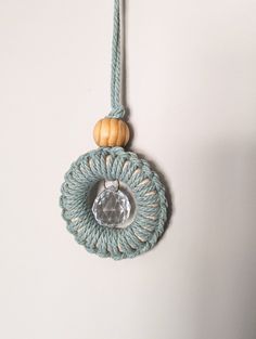 a white wall with a blue rope hanging from it's side and a wooden bead in the middle