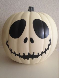 a white pumpkin decorated with black eyes and a jack - o'- lantern face