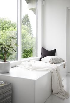 a white bed sitting next to a window in a room with lots of windows on both sides