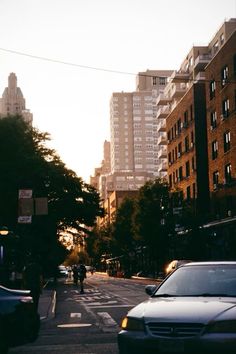 cars are parked on the street in front of tall buildings and people walking down the sidewalk