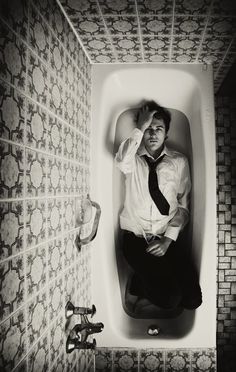 a man sitting in a bathtub wearing a tie