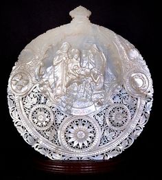 an intricately carved white glass dish with figures on it's sides and in the center