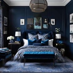 a bedroom with dark blue walls, white and blue bedding and pictures on the wall