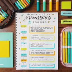 an open notebook with pens and markers next to other school supplies on a wooden table