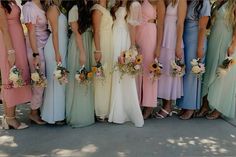 a group of women standing next to each other wearing dresses and holding bouquets in their hands