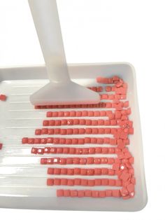 a person using a mop to clean red tiles on a white tray with orange squares