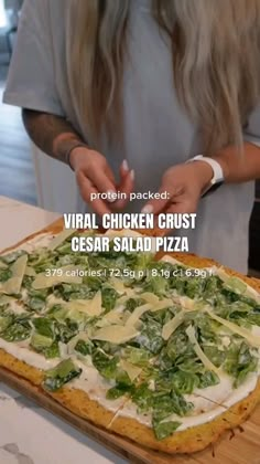 a woman standing in front of a pizza on top of a wooden cutting board