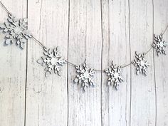 snowflakes are hanging from a string on a white wooden background with planks