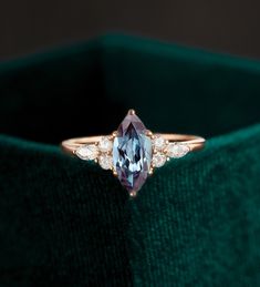 a blue and white diamond ring sitting on top of a green velvet box