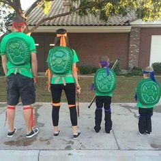 four people in green shirts are standing on the sidewalk with their backs turned to look like turtles