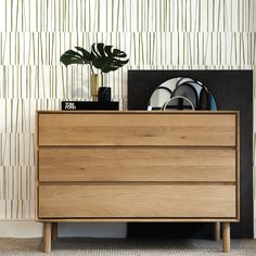 a wooden dresser sitting next to a plant on top of a table