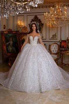 a woman in a white wedding dress standing next to a chandelier