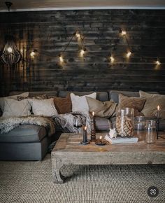 a living room filled with lots of furniture and lights hanging from the wall above it