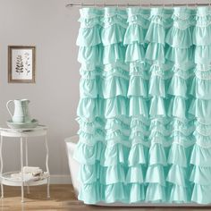 a shower curtain with ruffles on it and a white bath tub in the background