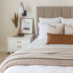 a bed with white linens and brown pillows