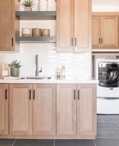 a kitchen with wooden cabinets and white tile backsplash, an appliance above the washer