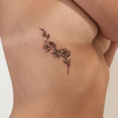 a woman's stomach with a small flower tattoo on the left side of her belly