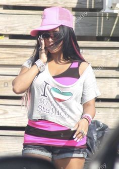 a young woman talking on her cell phone while wearing a pink hat and grey shirt