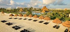 the beach is lined with thatched umbrellas and lounge chairs in front of an ocean resort