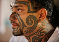 a man with tattoos on his face and neck