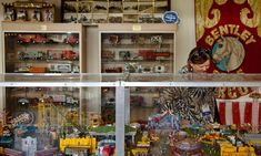 a woman looking through the glass at a display case with toy trains and cars in it